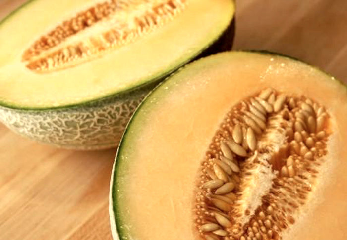 Cantaloupe melon with SeedsNow Heart of Gold seeds, showing ripe orange flesh and green rind on a white background.